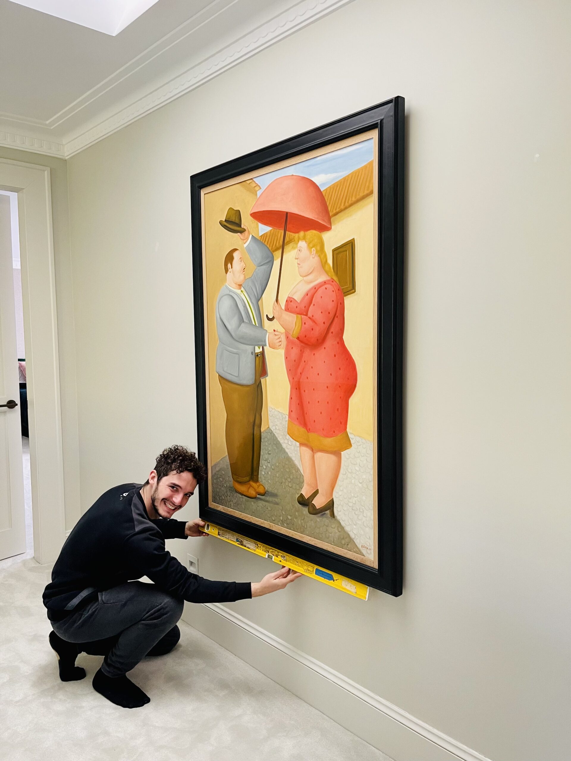 A worker checking the levels of a new piece of art he installed on a wall in a house